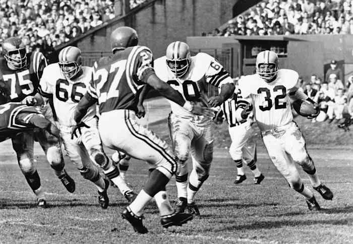 Cleveland Browns running back Jim Brown (32) carries the ball behind the blocking of John Wooten (60) and Gene Hickerson (66) against the Philadelphia Eagles defenders Irv Cross (27) and John Meyers (75) at Cleveland Municipal Stadium